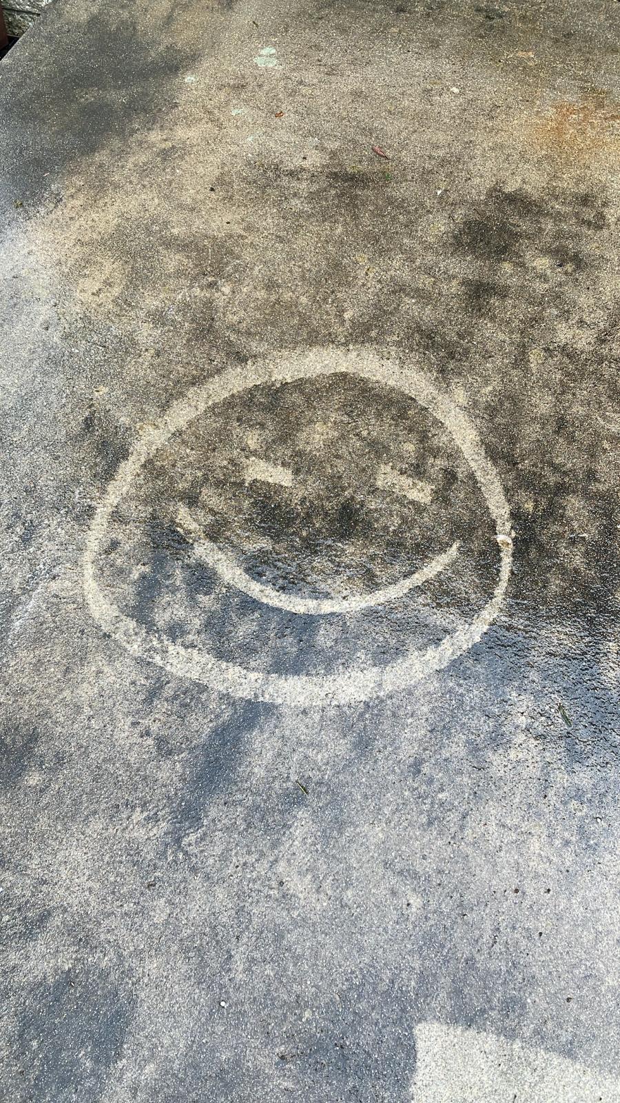 A smiley face washed clean into a grimy wall
